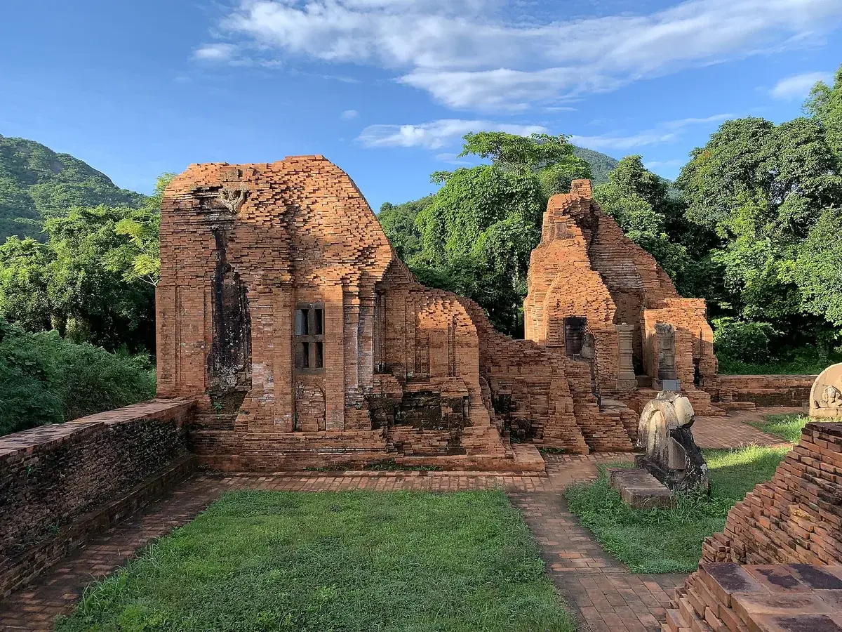Brick ruins of Cham temples in Group A at My Son, with lawns and stone paths in front and forested hills behind