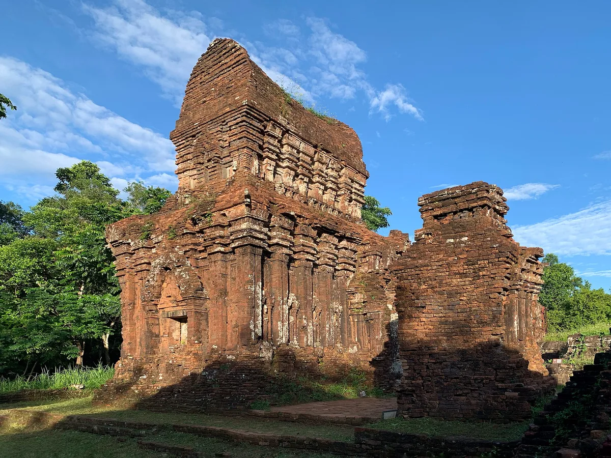 Two weathered brick Cham towers in Groups B, C and D at My Son Sanctuary under a blue sky