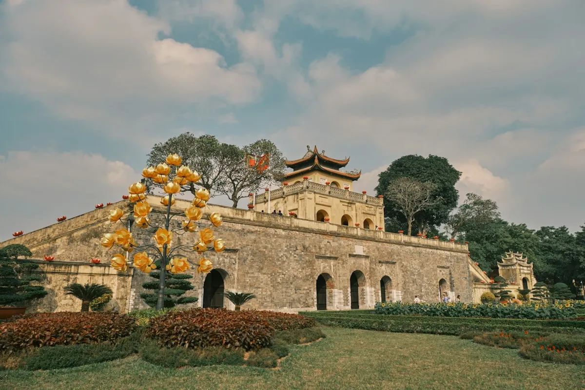 Doan Mon Gate of the Thang Long Imperial Citadel in Hanoi, a yellow pavilion on a stone wall behind gardens
