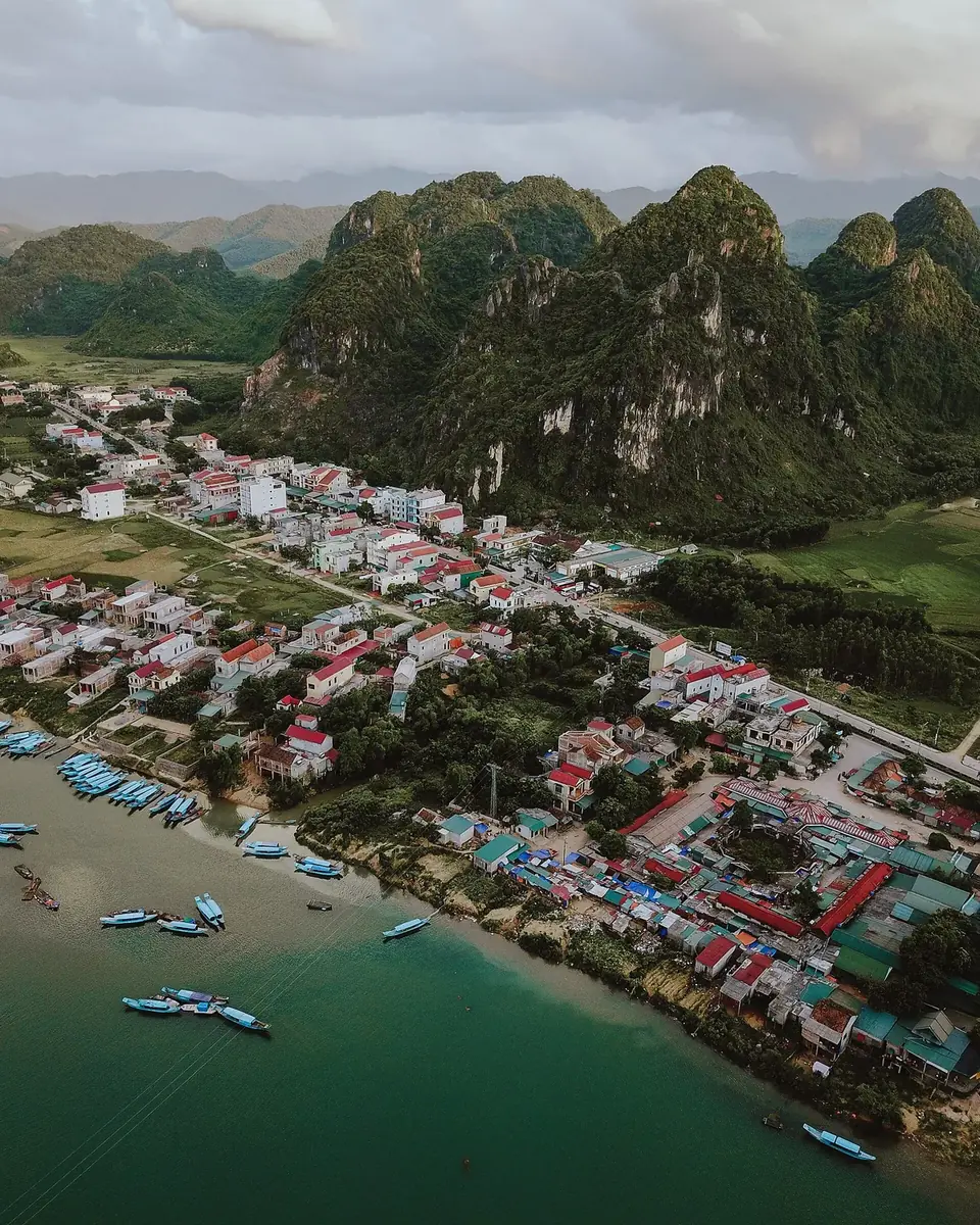 Boats moored on the Son River below the town of Phong Nha, with forested karst peaks behind