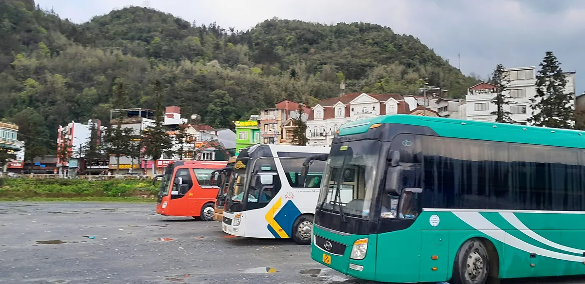 Long-distance buses parked in Sa Pa town with hotels and forested hills behind