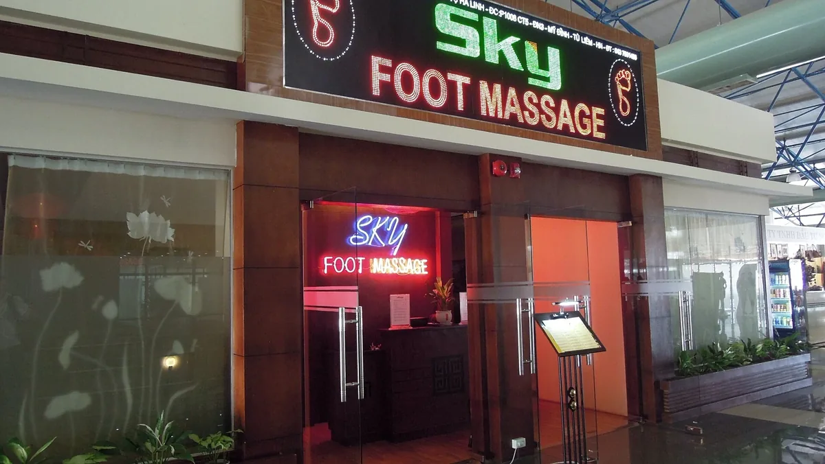 The glowing red and green sign of a foot massage shop inside a terminal at Noi Bai International Airport, Hanoi