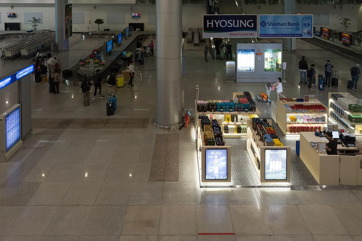 Baggage claim area of the international arrivals hall at Tan Son Nhat airport, with duty-free kiosks and bank ATMs