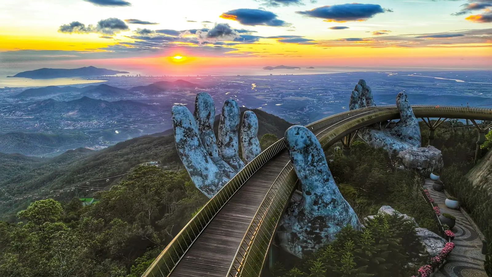 The Golden Bridge held up by giant stone hands above a valley at Ba Na Hills