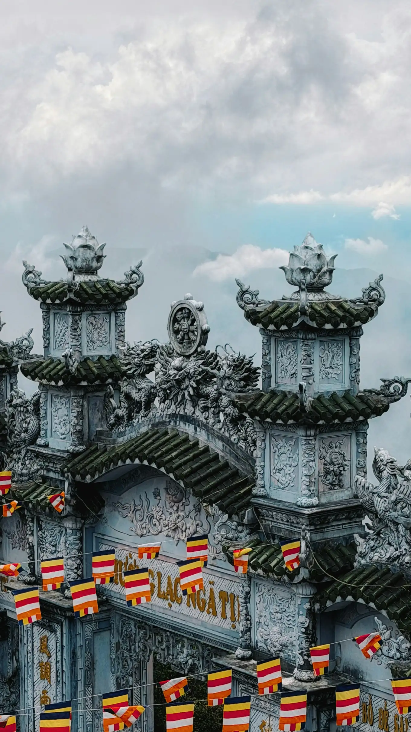 An ornate stone temple gate with dragon carvings and prayer flags at Ba Na Hills