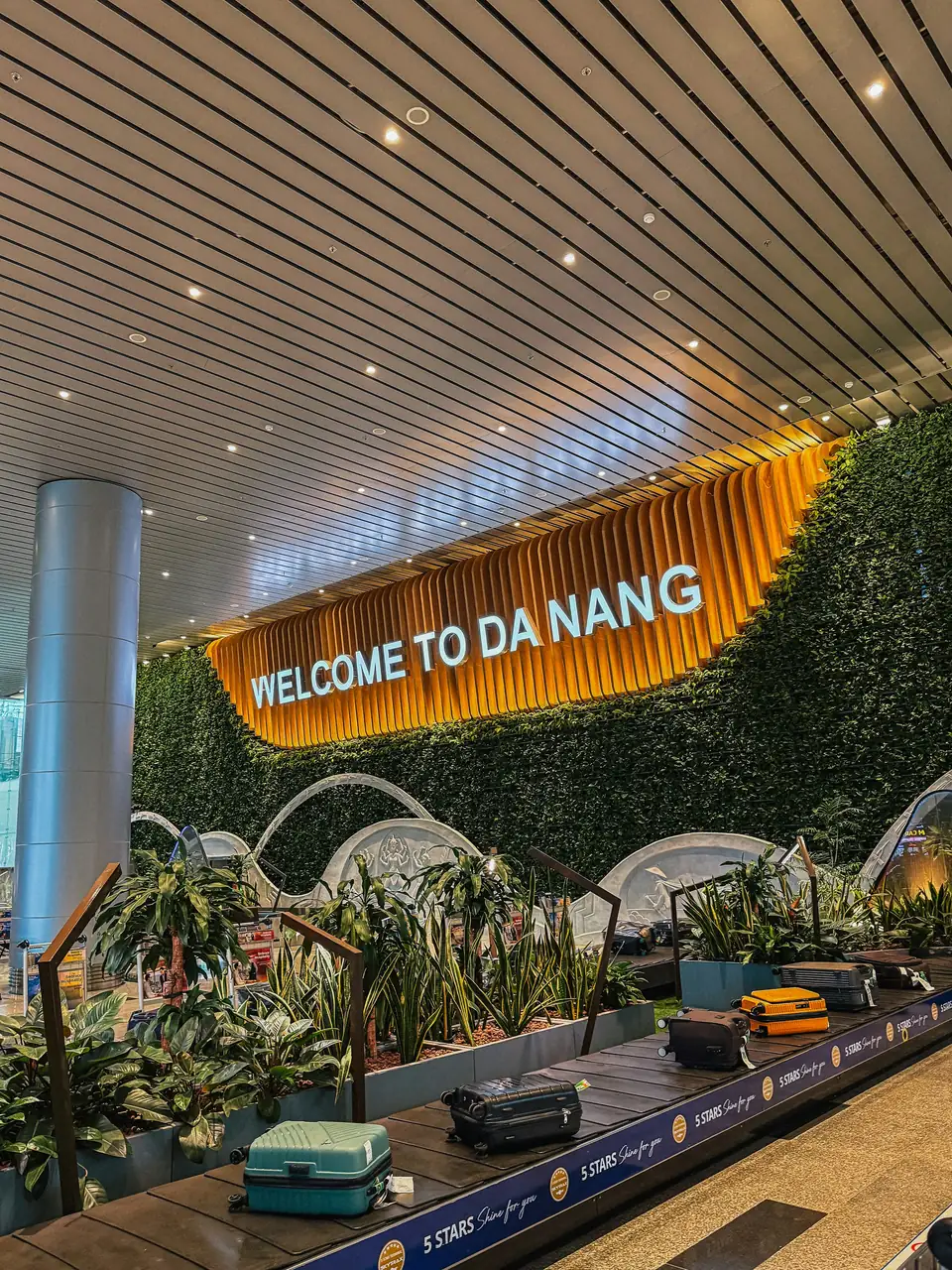 The baggage hall at the airport, a 'Welcome to Da Nang' sign on a green wall