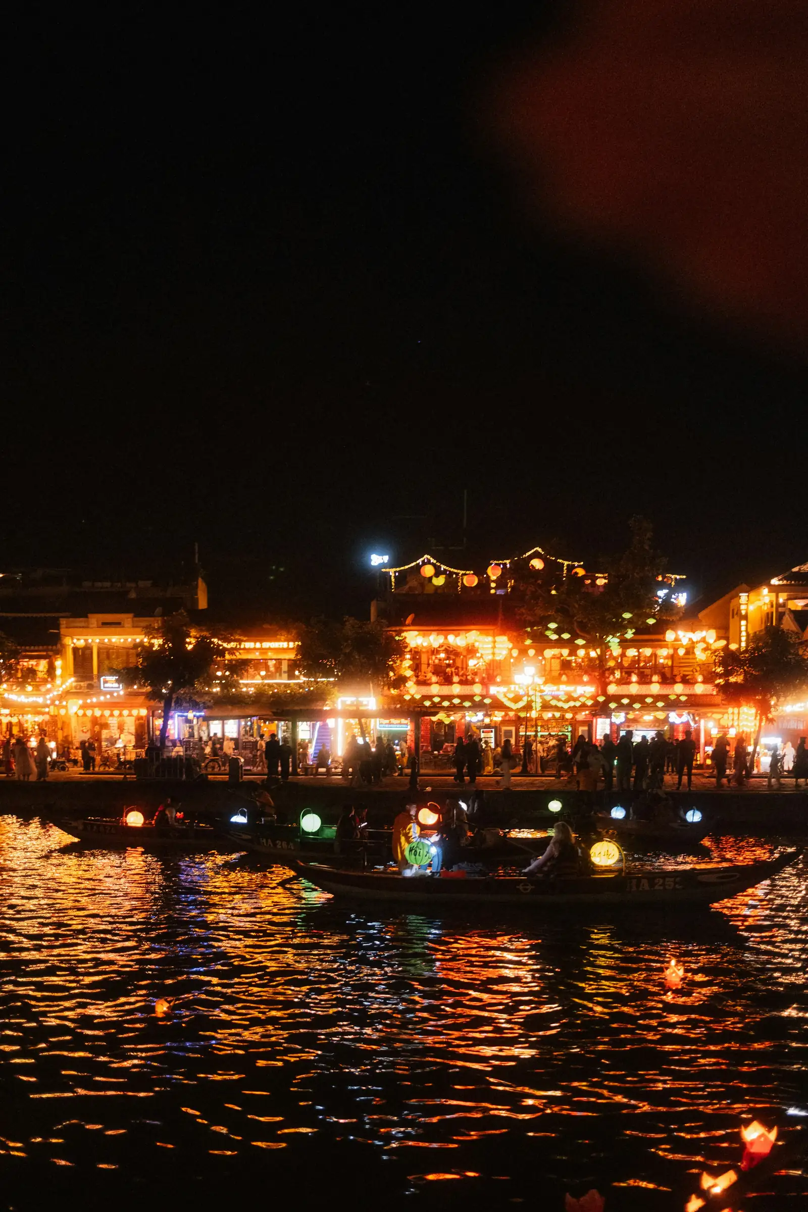 Small wooden boats with glowing lanterns on the river at night
