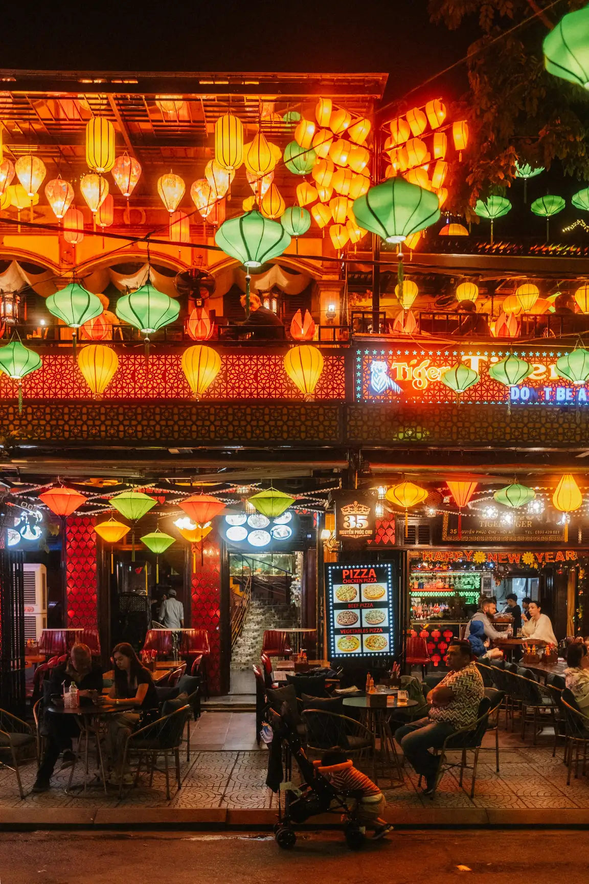 People dining at tables under hanging lanterns