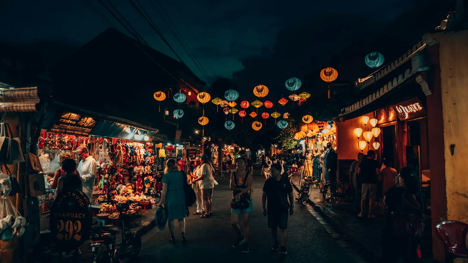 People walking under rows of coloured lanterns at night