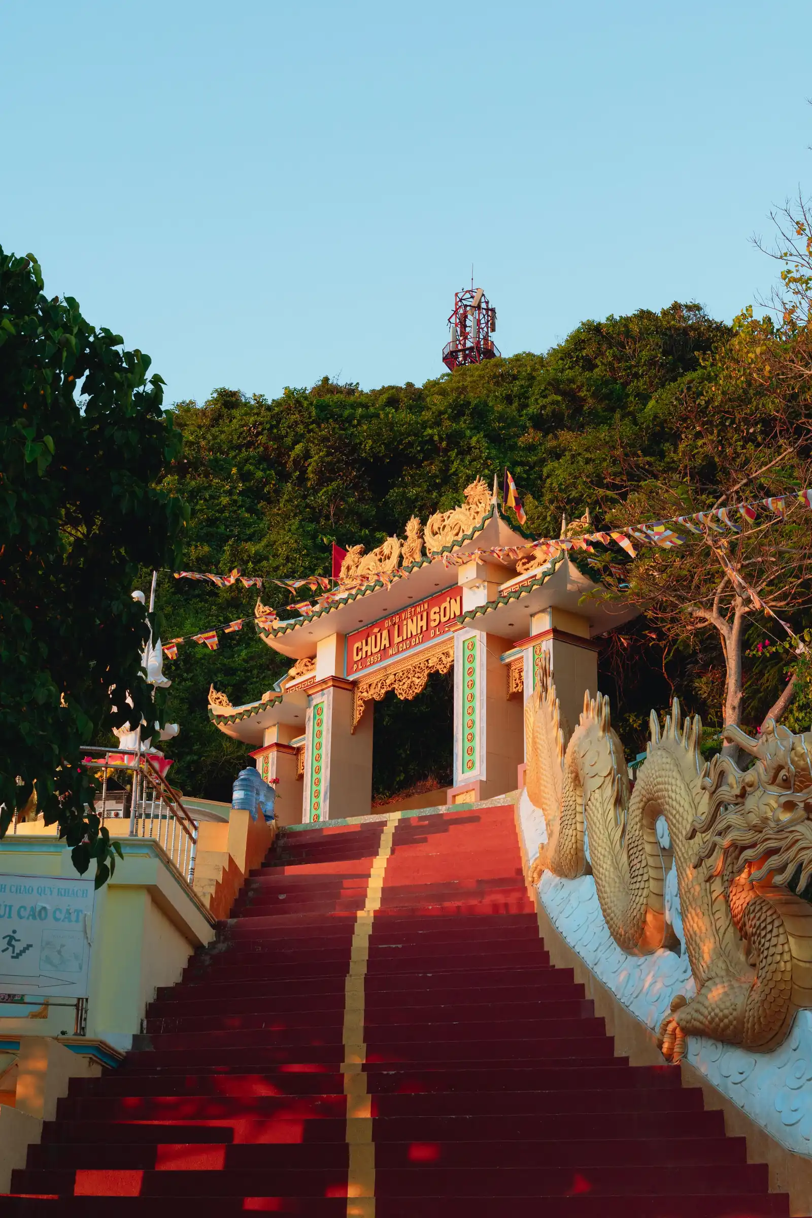 Red steps flanked by golden dragons climbing to the gate of Linh Son pagoda on Phu Quy