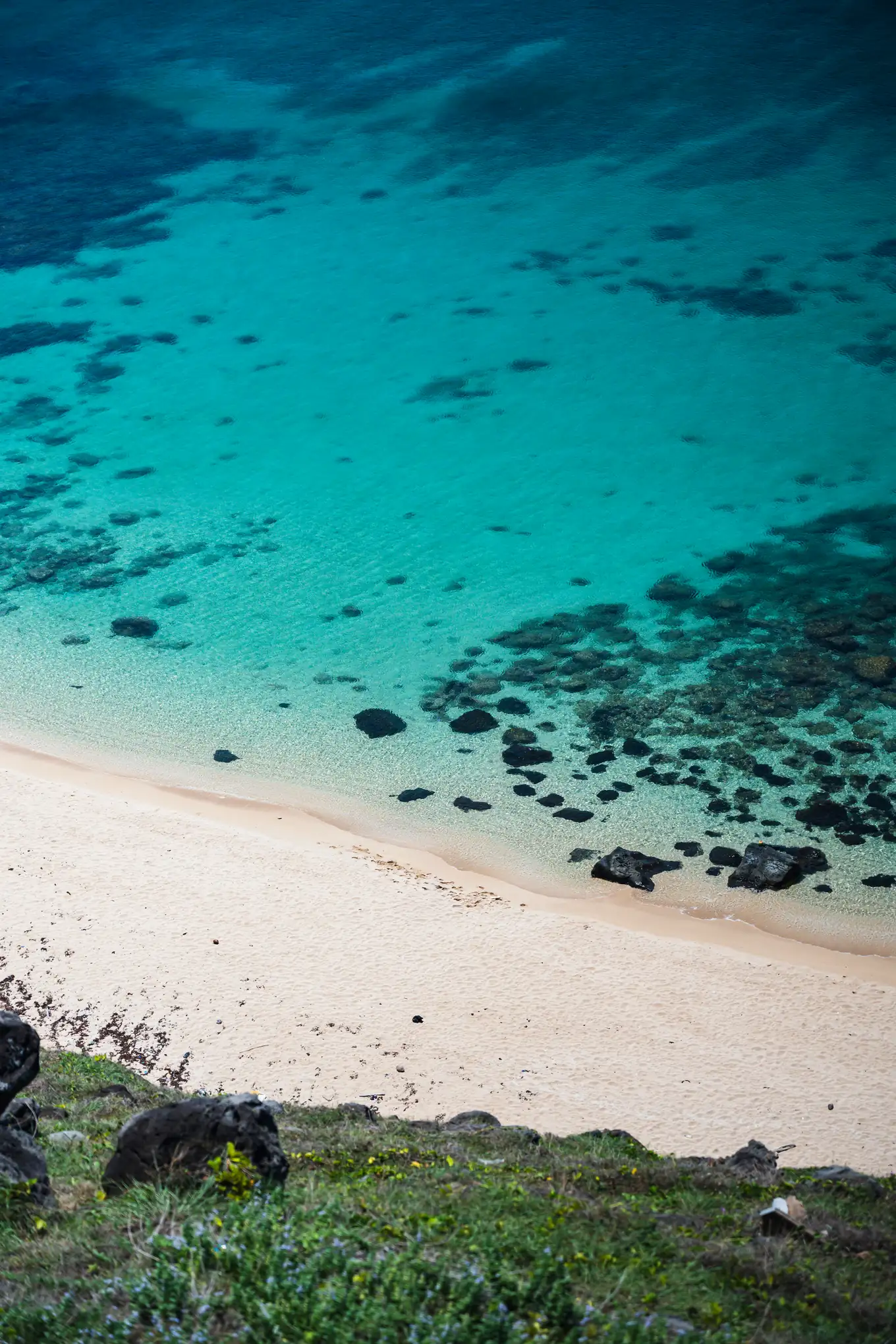 Turquoise water over coral and a white sand beach on Phu Quy, seen from the slope above