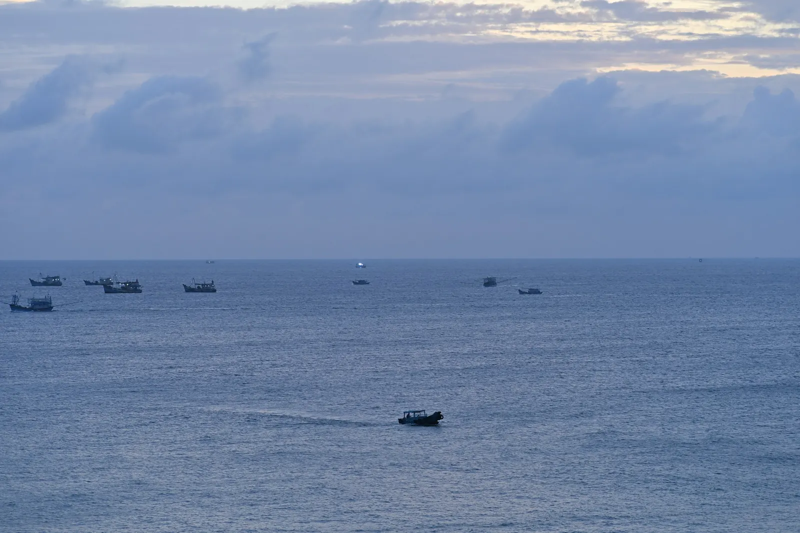 Fishing boats on a calm sea under a cloudy dawn sky off Phu Quy