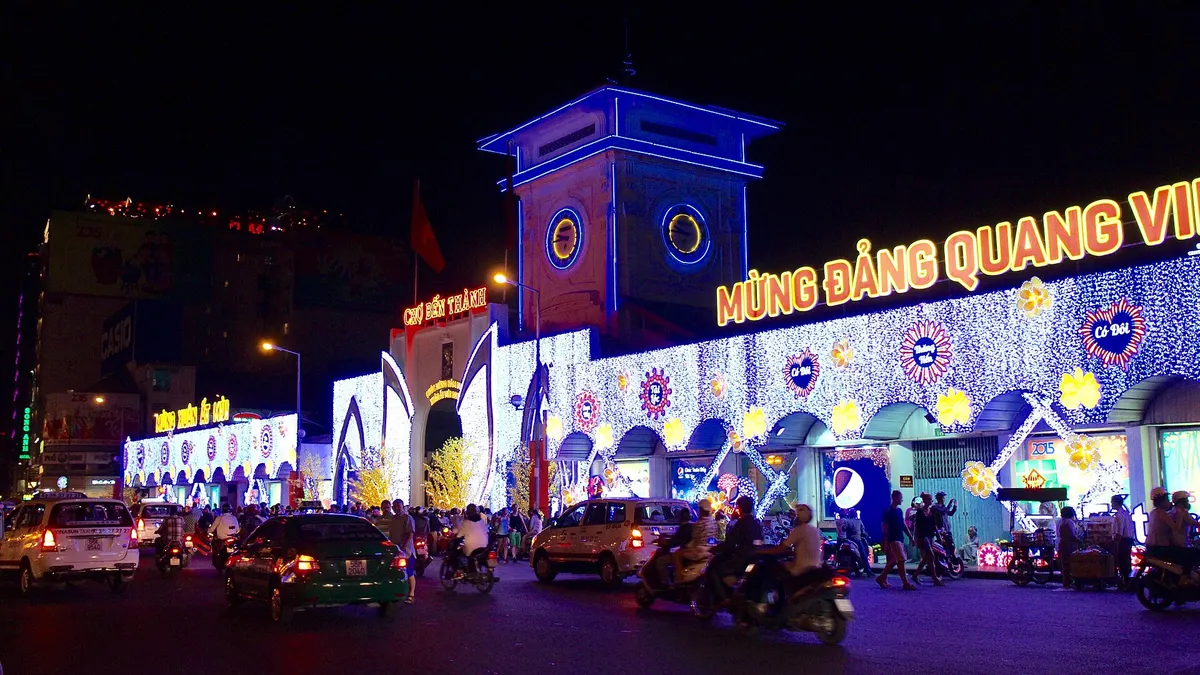 The market gate lit up at night in blue and gold, traffic passing in front