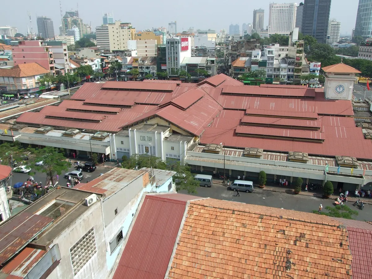 The market's long red-tiled roofs and clock tower seen from a high building, with the city skyline behind