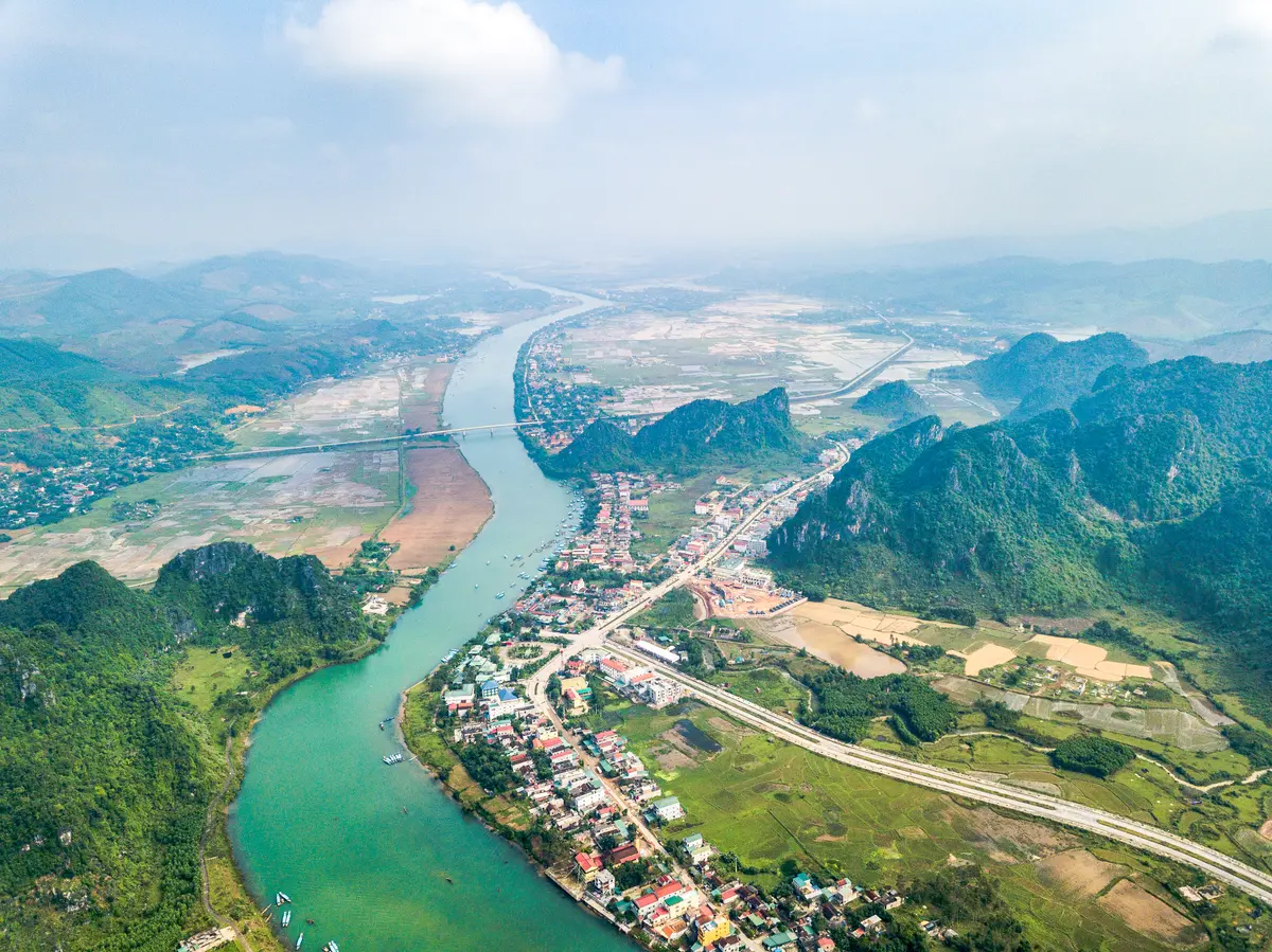 Aerial view of the Son River curving through green farmland and villages between limestone hills near Phong Nha