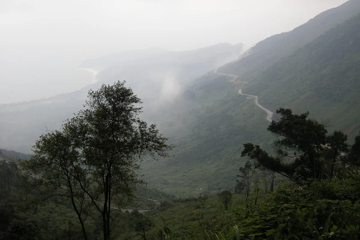 Fog filling the valleys below the Hai Van Pass, with a thin road visible along the slope