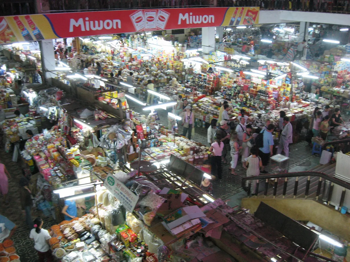 The crowded ground floor of Han Market seen from the balcony above, with stalls and hanging banners