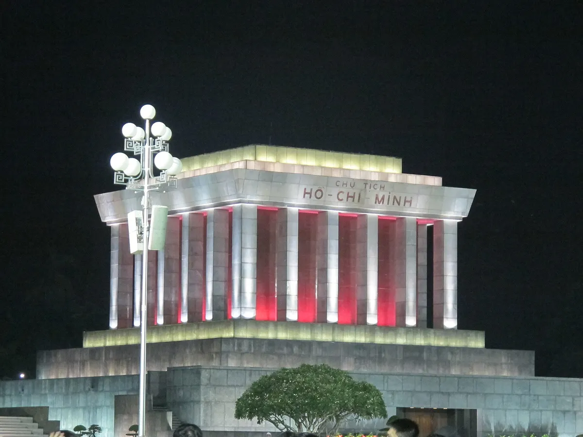 The mausoleum lit up at night, its columns glowing red above a pale granite base