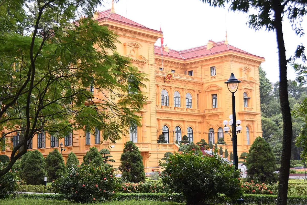 The ornate yellow French colonial Presidential Palace behind trees and a lamp post