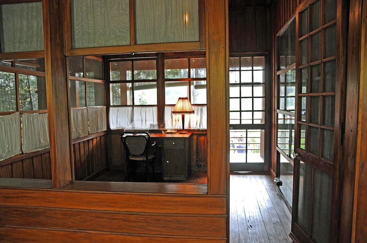 Ho Chi Minh's study seen through an open wooden partition, a desk and lamp by the window