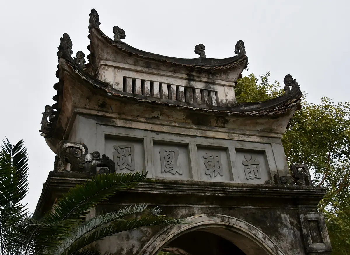 Close view of the curved, layered roofs of a stone gateway at Hoa Lu, with Chinese characters on its face