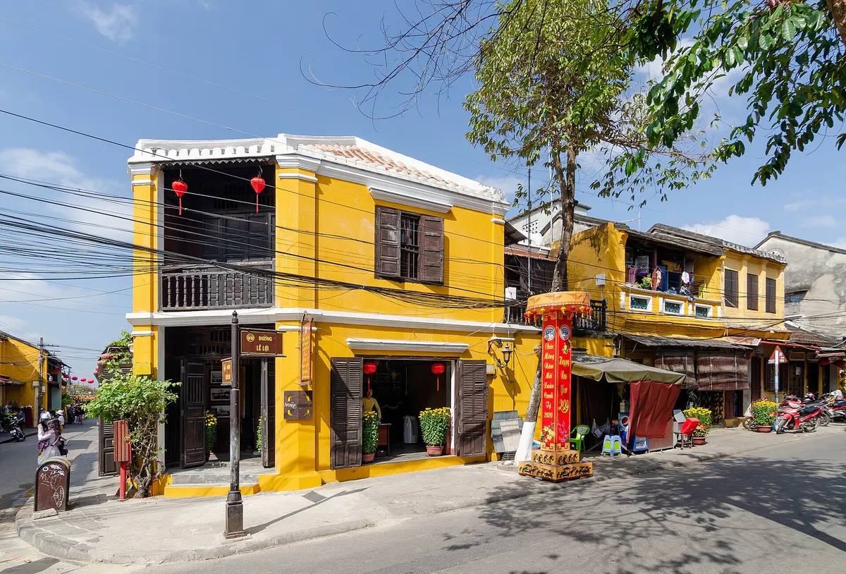 A corner of the Ancient Town with yellow two-storey houses, red lanterns and a quiet street in daylight