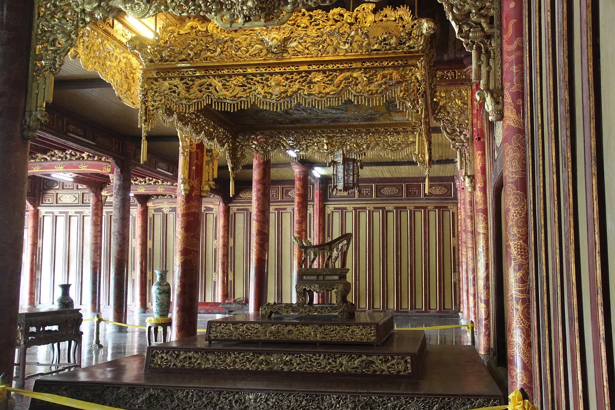 The gilded throne canopy inside Thai Hoa Palace, with red lacquered columns behind a roped-off dais