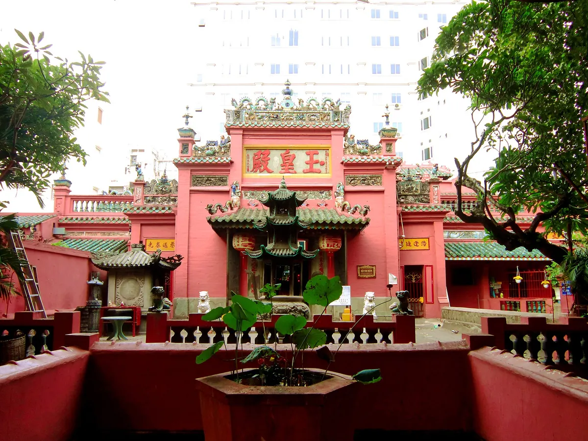 Red pagoda halls seen from a raised courtyard, with a potted plant on a low red wall in front