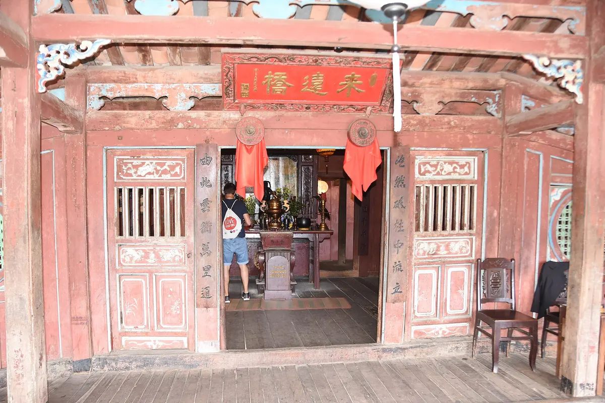 Red-painted wooden doors opening onto a small altar room inside the bridge