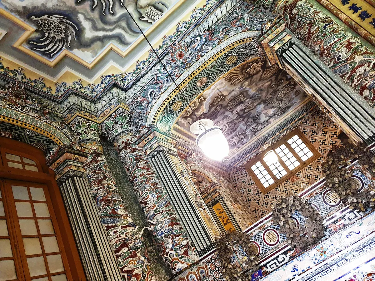 Inside the tomb, walls and a vaulted ceiling covered in coloured porcelain and glass mosaics around a lamp