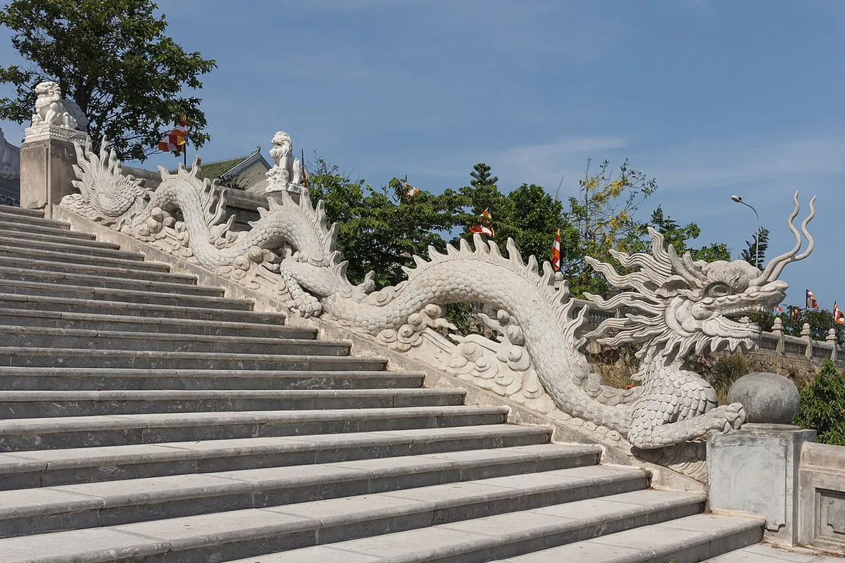 A carved stone dragon running down the balustrade of a wide stairway at Linh Ung Pagoda