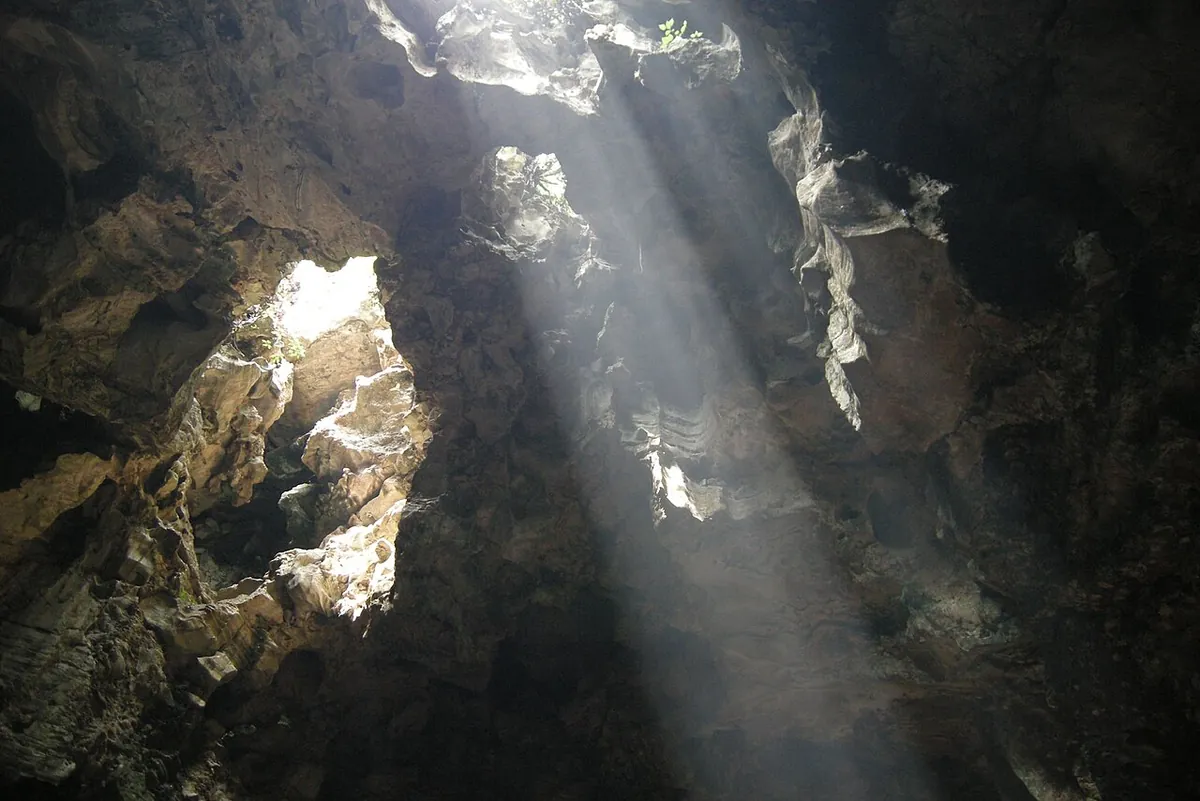 Sunlight falling in a shaft through smoke inside Huyen Khong cave