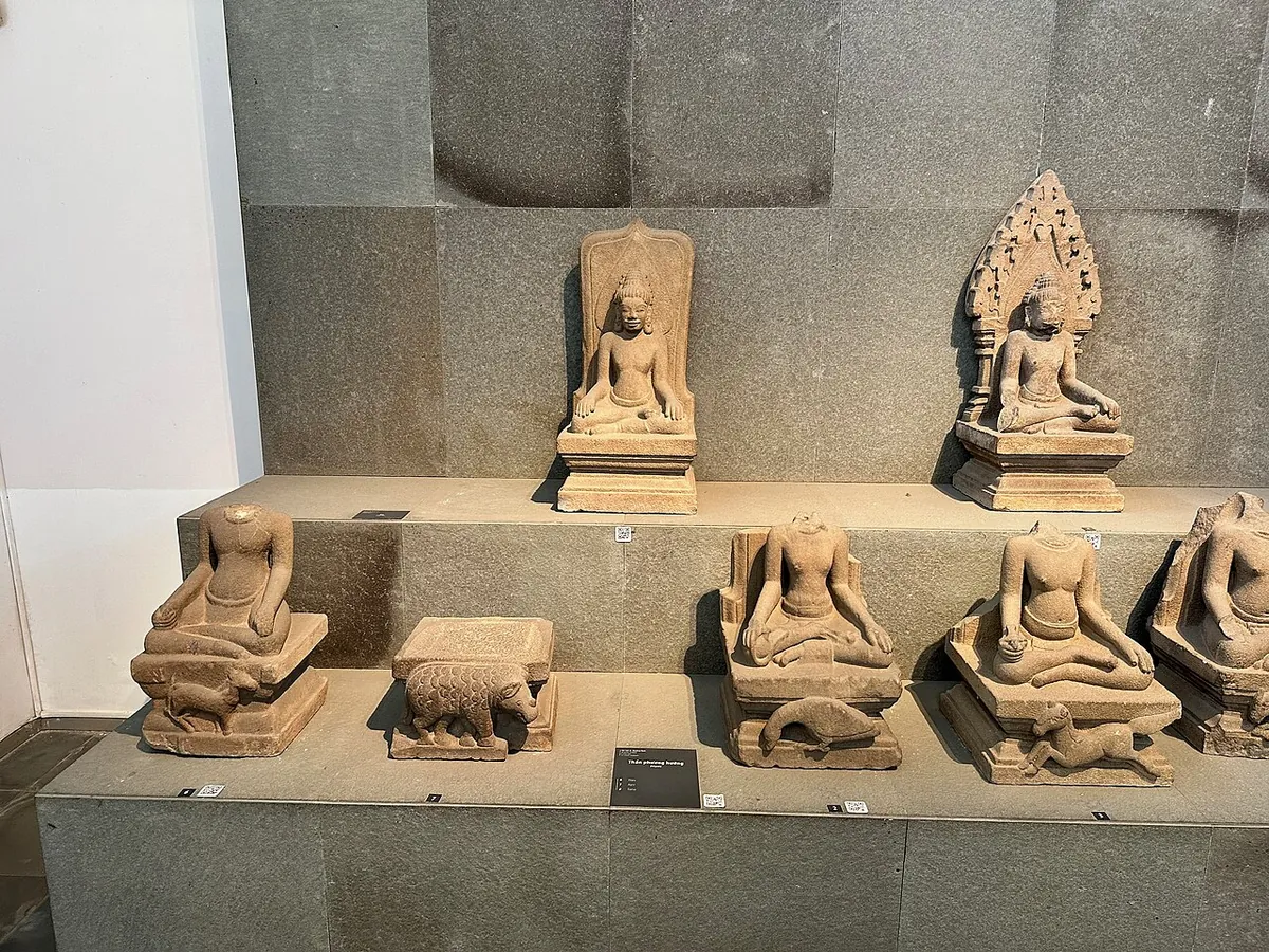 A shelf of seated Cham deities in sandstone in a museum gallery