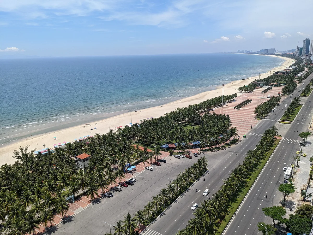 The Da Nang shoreline from above: a coastal road lined with palm trees, a strip of sand and the sea