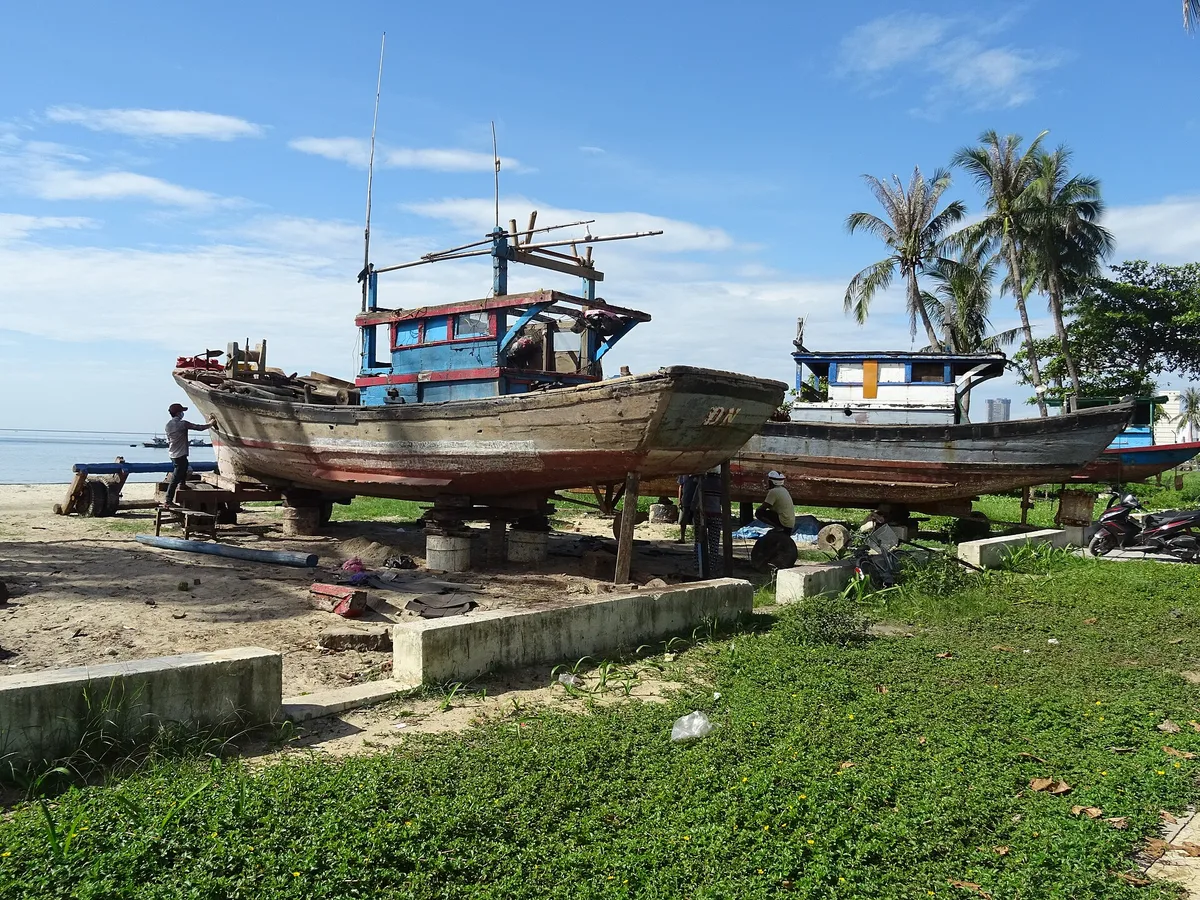 Wooden fishing boats pulled up on a grassy patch above My Khe Beach