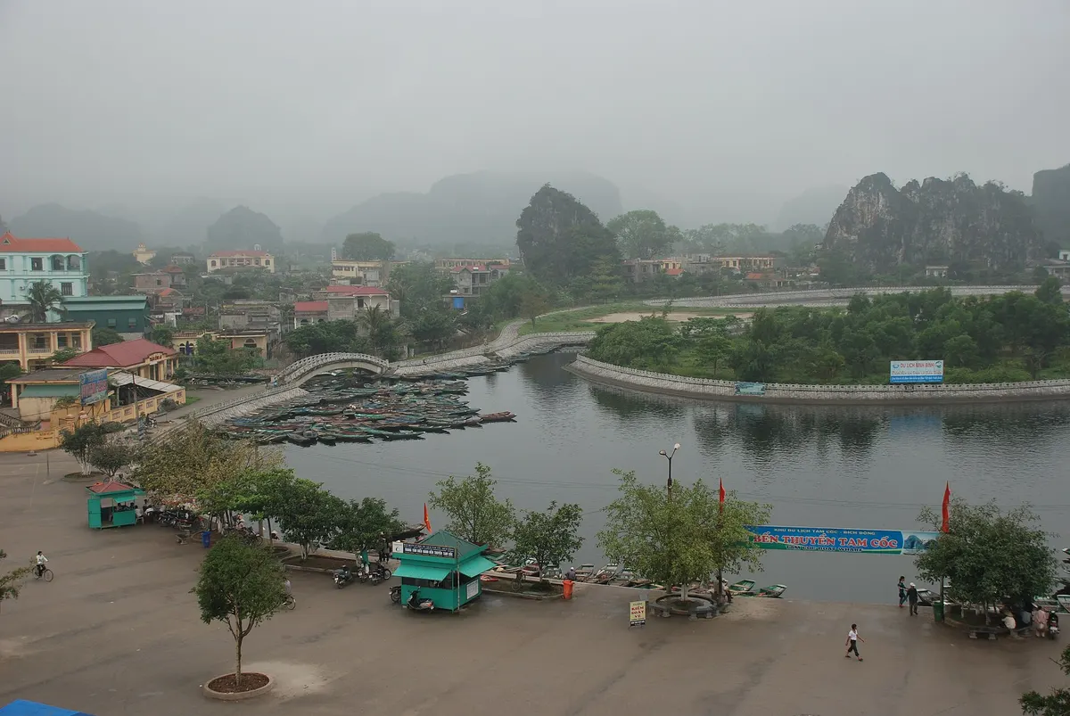 The Tam Coc boat landing seen from above on a hazy day, with boats moored along a curved embankment