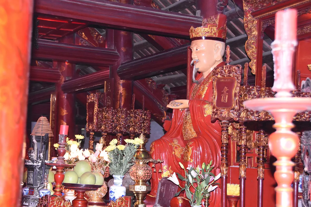 A red and gold altar inside the Temple of Literature with a statue of Confucius surrounded by offerings