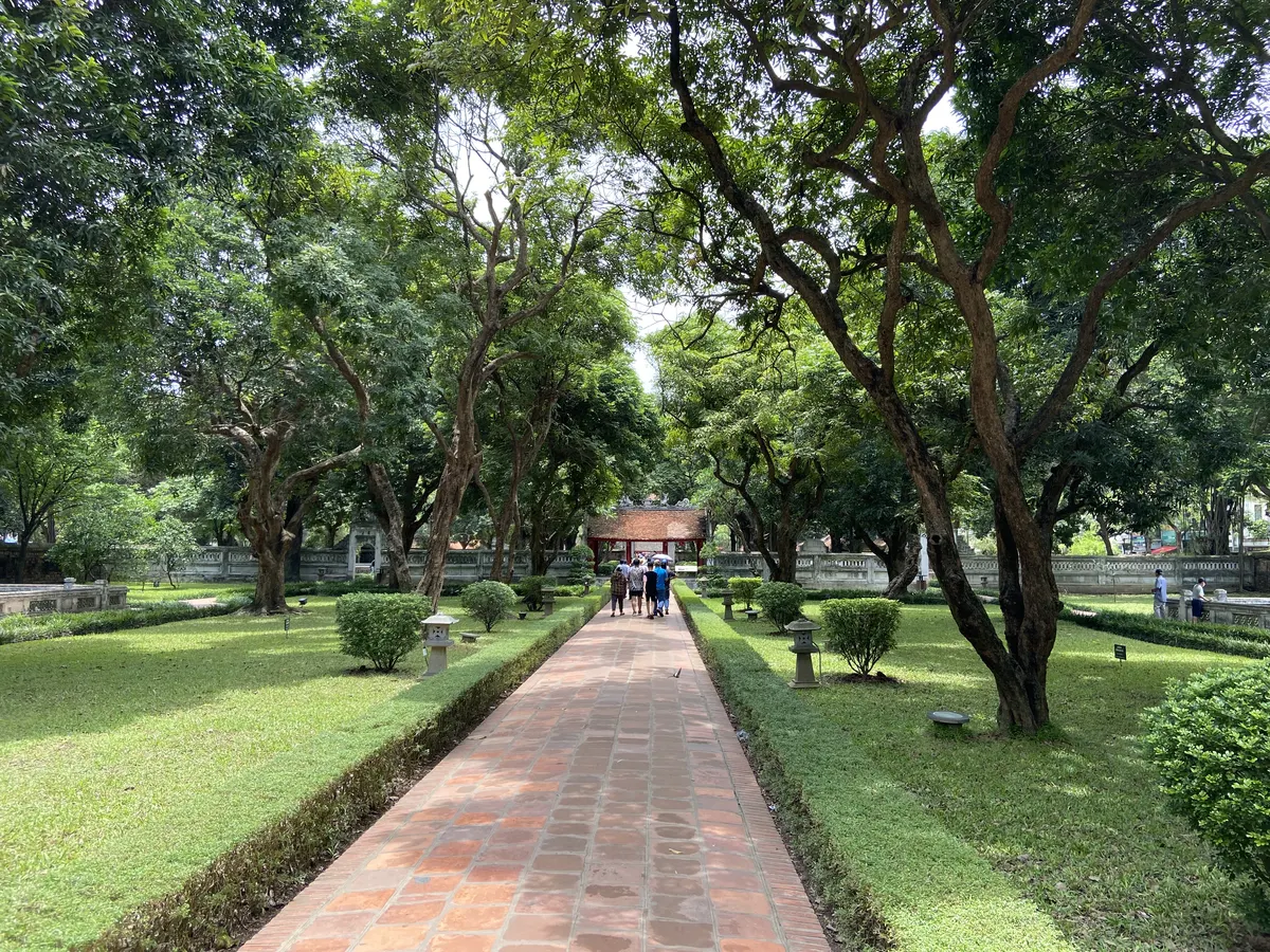 A tree-lined brick path leading through a lawn toward a gate in the Temple of Literature