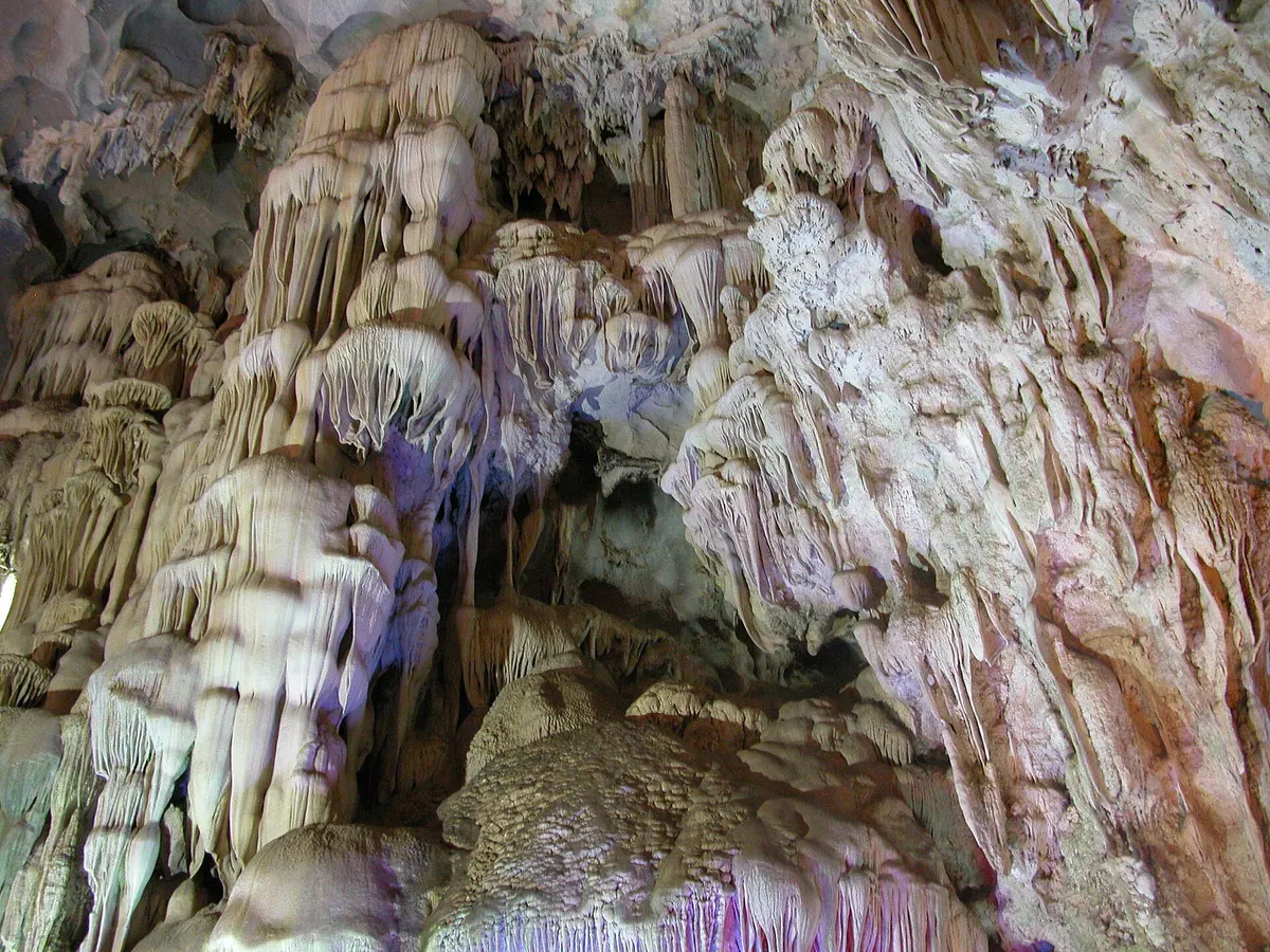 Creamy stalactite curtains and flowstone filling the upper part of Thien Cung Cave