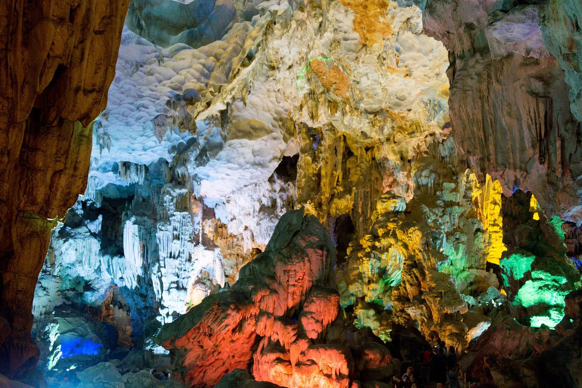 Cave formations lit in blue, green, red and yellow in Thien Cung Cave