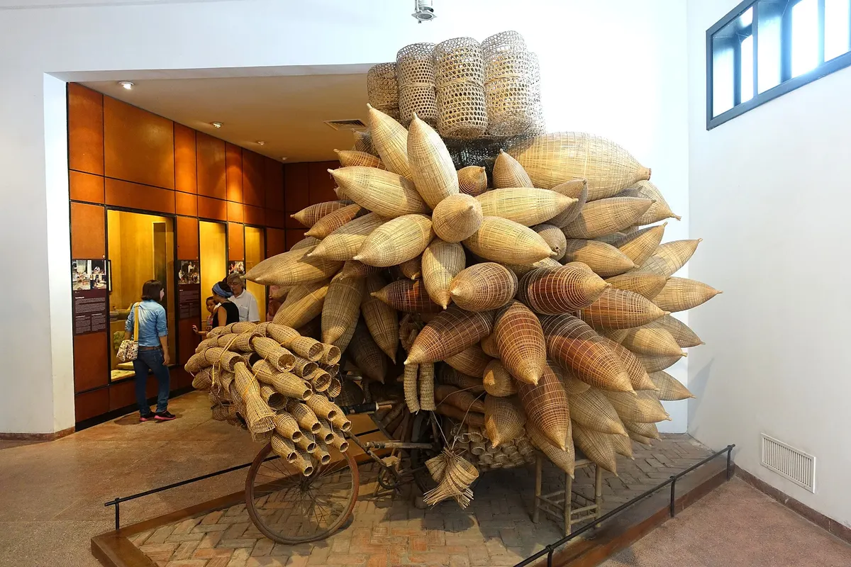 An old bicycle loaded with dozens of bamboo fish traps, on display in a museum hall