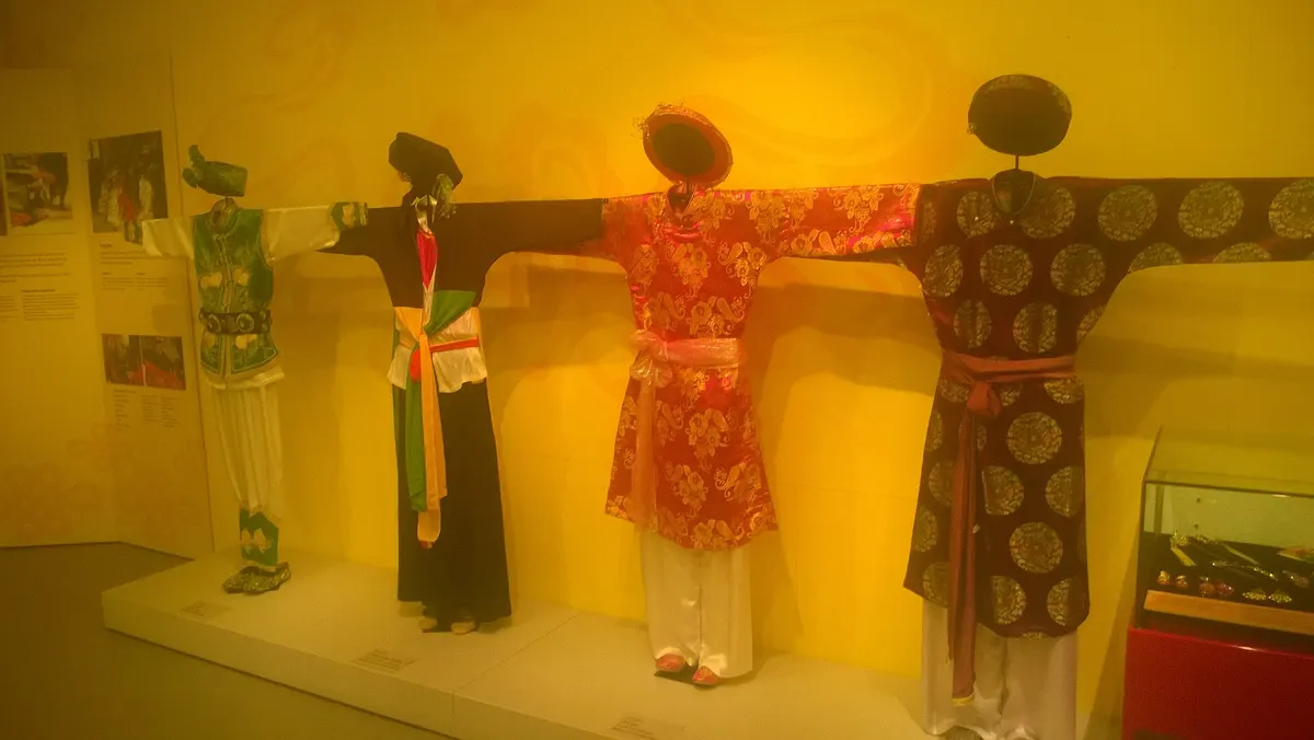 Mannequins in traditional costumes standing in a row against a yellow wall