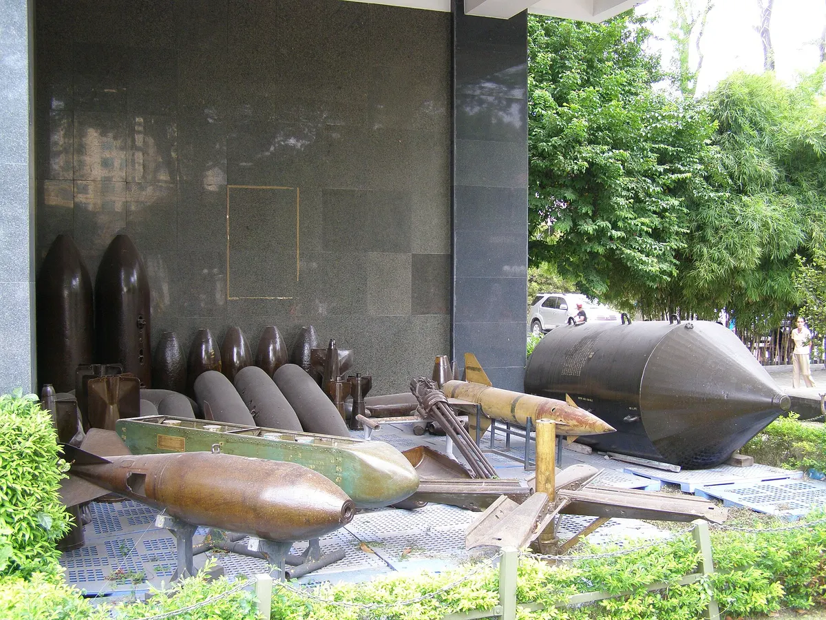 Bomb casings and shells of different sizes laid out beside the museum building, a large finned bomb at the right