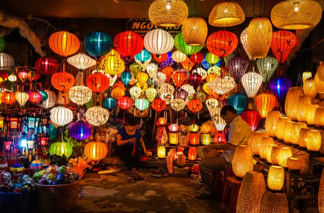 A lantern maker at work among hundreds of glowing silk lanterns in Hoi An