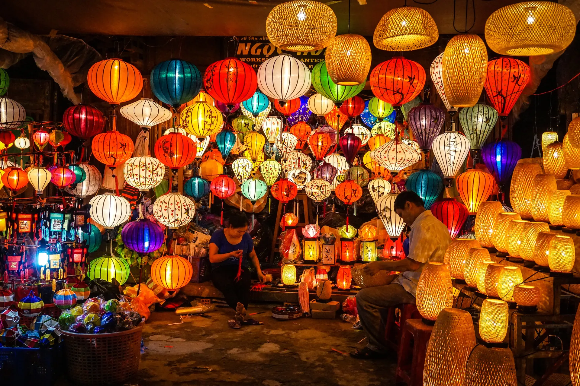 A lantern maker at work among hundreds of glowing silk lanterns in Hoi An