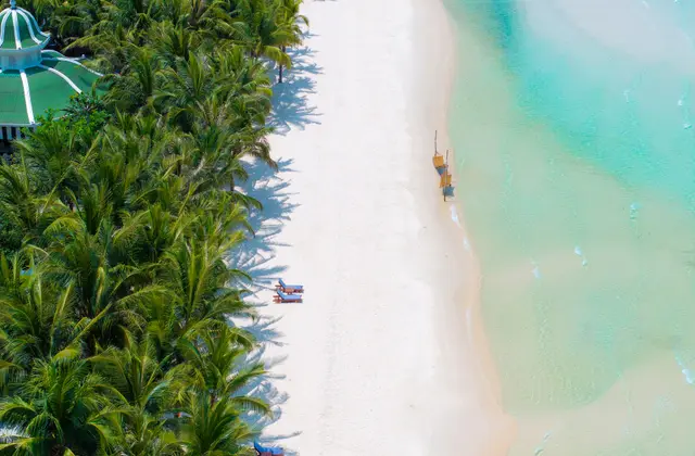 Aerial view of a white sand beach and turquoise shallows fringed by palms on Phu Quoc